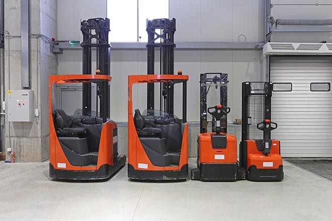 three forklifts unloading trucks in a distribution center